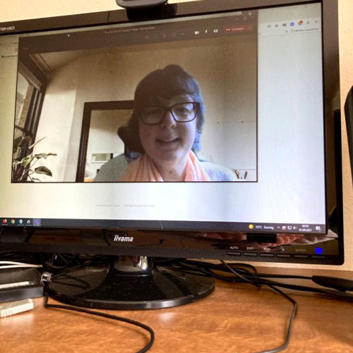 Eine Webcam zeichnet SMA-Betroffene Camilla auf, sodass sie im Bildschirm eines Monitors auf einem Arbeits-Schreibtisch zu sehen ist.