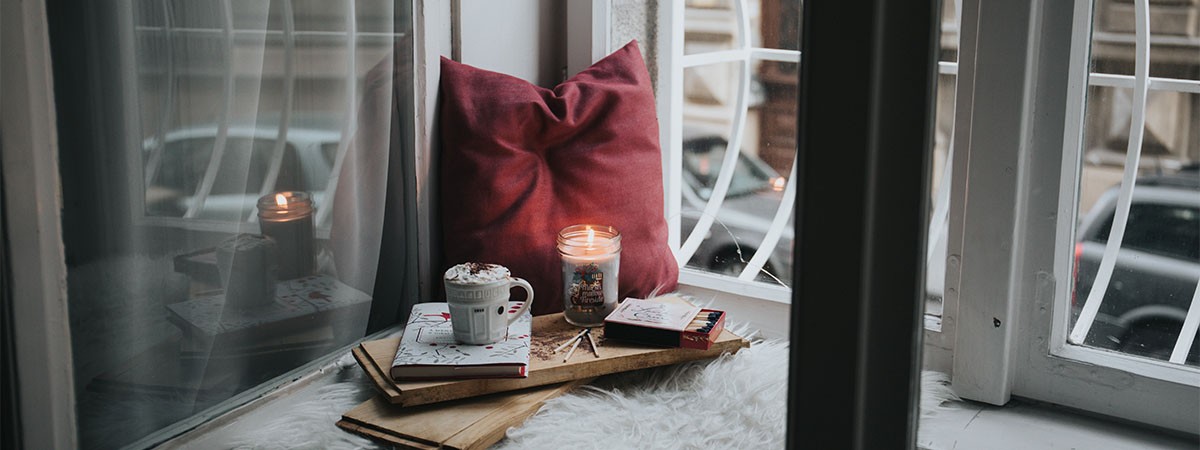 Auf einem braunen Ledersessel liegen ein weißes Kissen, eine Decke und eine weiße Kaffeetasse.