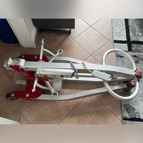 Ein mobiler Tragelifter zum Heben und Transportieren von Menschen mit körperlichen Einschränkungen ist zusammengeklappt und liegt auf dem Boden.