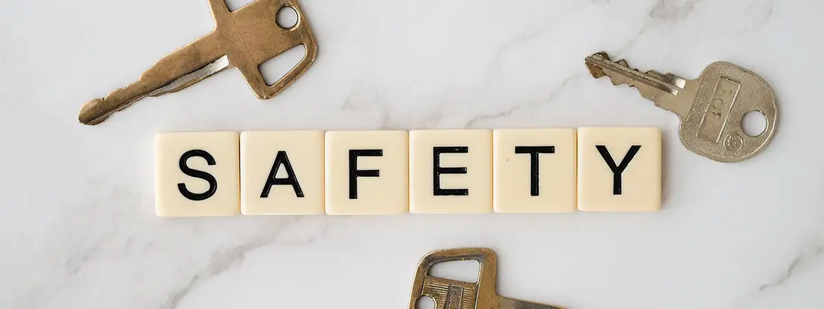 Ein Bild mit Scrabble-Buchstaben, die das Wort „SAFETY“ bilden. Darum befinden sich drei Schlüssel, die auf einem Marmortisch liegen. 