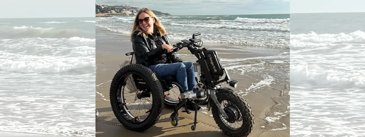 Ein Foto von Svenja auf einem elektrischen Rollstuhl-Zuggerät am Strand.