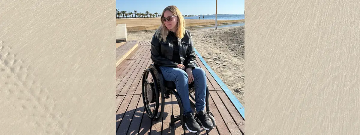 Ein Foto von Svenja im Rollstuhl auf einem Holzsteg am Strand.
