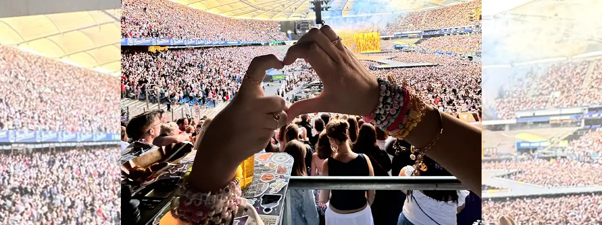 Ein Foto von Vanessa und ihrer Begleitung, die gemeinsam ein Herz mit ihren Händen formen, während sich im Hintergrund viele Konzertbesucher befinden.