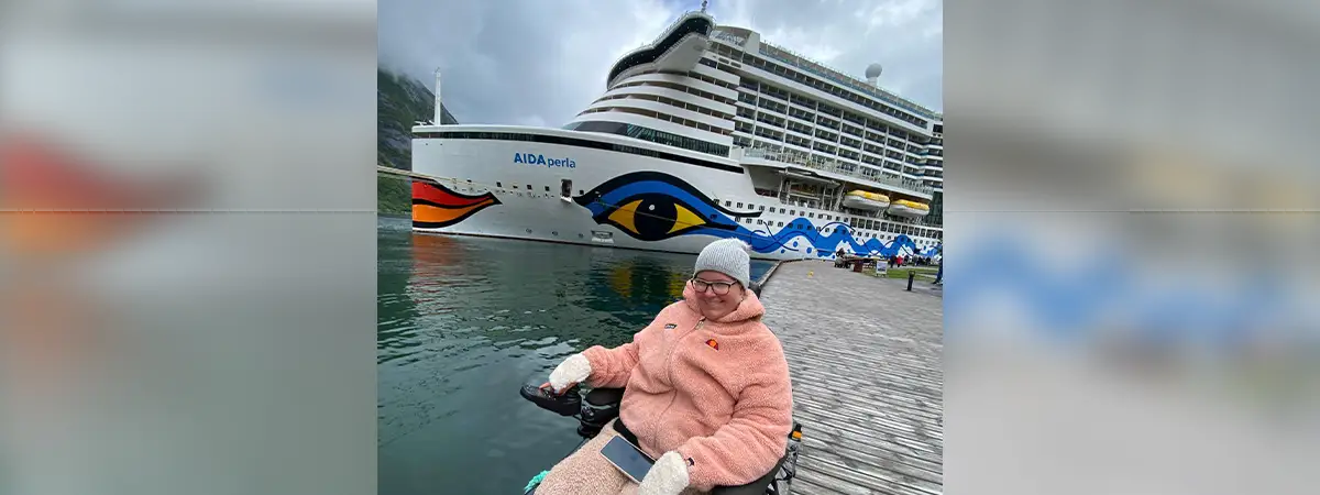 Alina, die sich am Wasser auf einem Steg befindet – hinter ihr ist das AIDA Kreuzfahrtschiff.