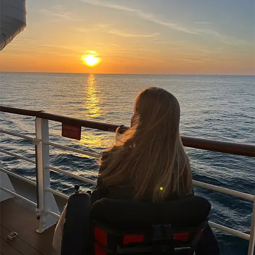 Ein Foto von Lilli, während sie zum Sonnenuntergang und zum Meer schaut.