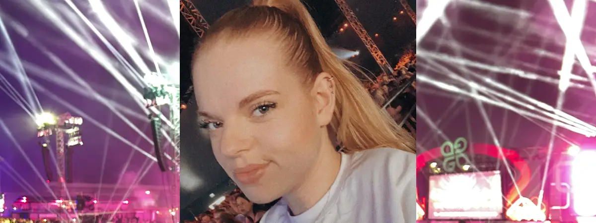 Ein Foto von Lilli, die ein Selfie von sich auf einem Konzert macht, während sie in die Kamera lächelt.