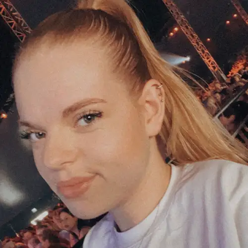Ein Foto von Lilli, die ein Selfie von sich auf einem Konzert macht, während sie in die Kamera lächelt.